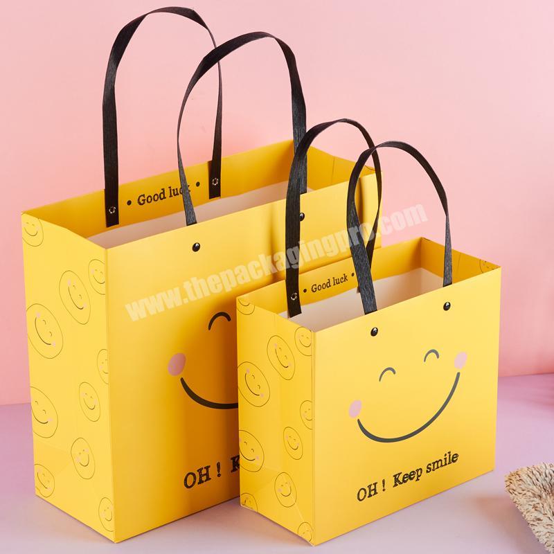 Hot sale happy face yellow art paper cartoon kraft christmas gift paper bag with plastic handle