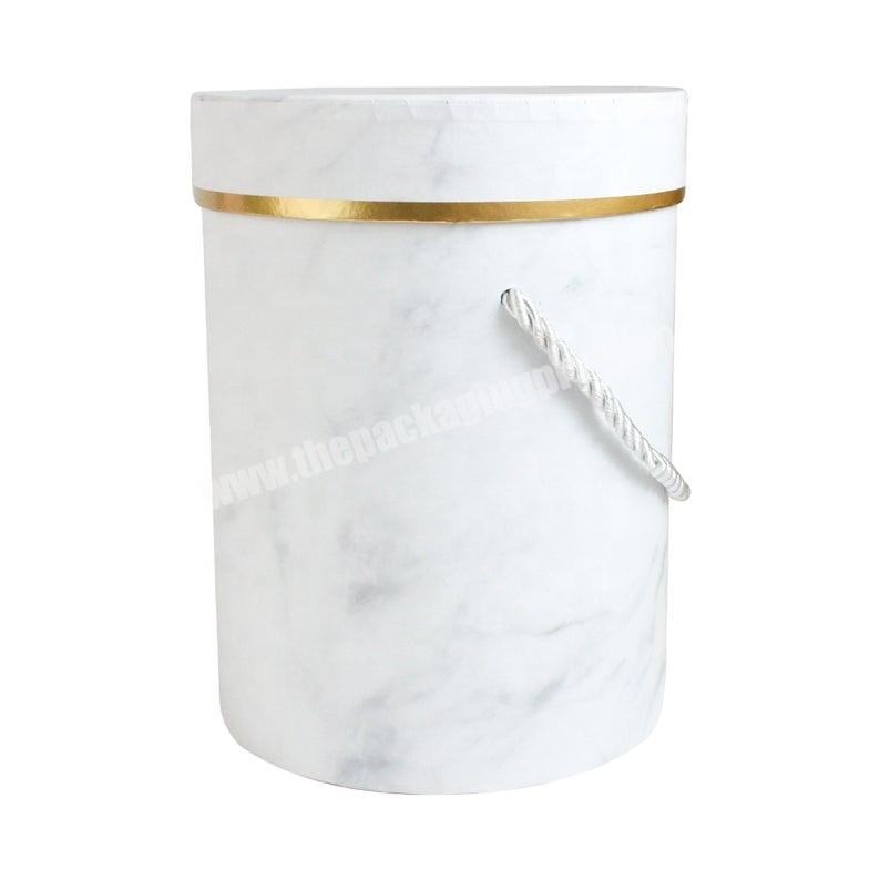 Tall cylindrical gift box marble print cream gold rimmed lid and black carry handle